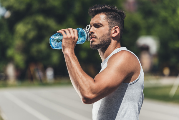sporty young man drinking water after workout - Photo, Image