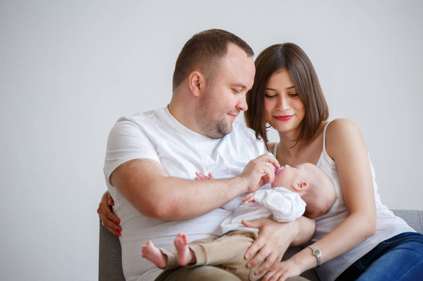 Picture of happy married couple with newborn baby sitting on sofa - Zdjęcie, obraz