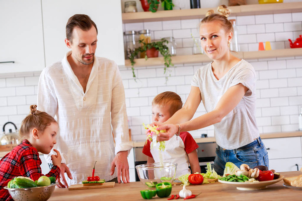 Immagine di giovane madre e padre con figlio e figlia che preparano la colazione
 - Foto, immagini