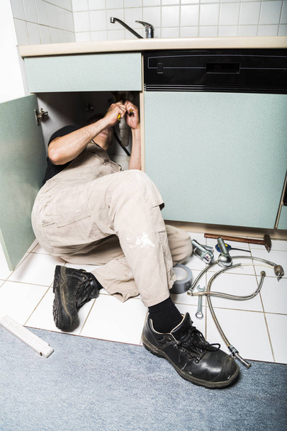 specialist male plumber repairs faucet in kitchen - 写真・画像