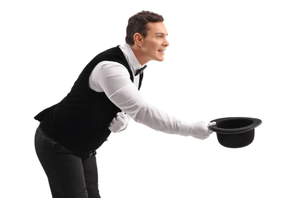 Waiter bowing down and taking his hat off isolated on white background - Foto, Bild