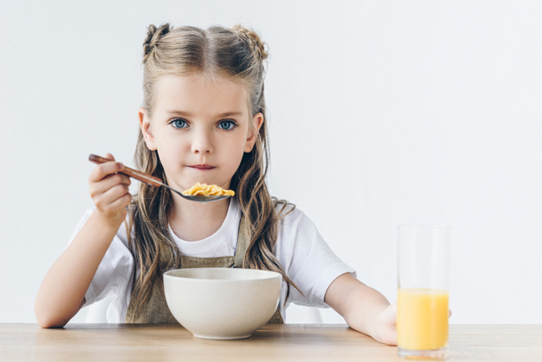 little schoolgirl eating healthy breakfast isolated on white and looking at camera - Foto, immagini