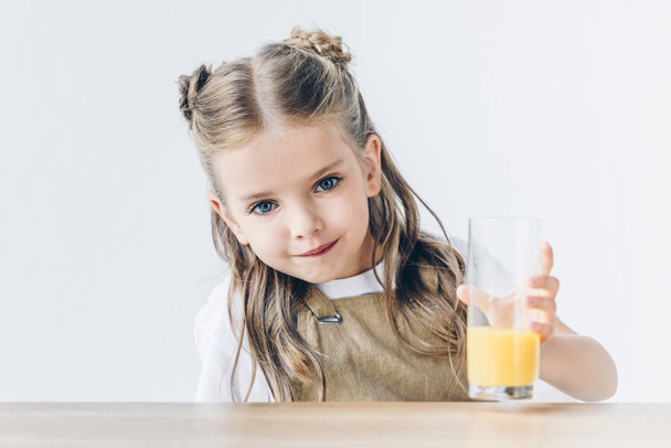 schattige kleine schoolmeisje met glas sinaasappelsap geïsoleerd op wit - Foto, afbeelding