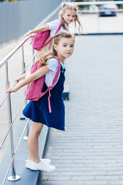 little schoolgirls with pink backpacks playing on street - Foto, immagini
