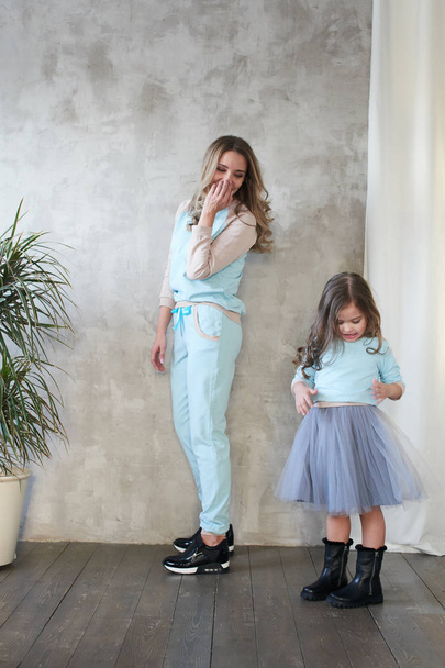 Mom and daughter in same clothes having fun at photo shoot in studio, lookbook concept  - Foto, Bild