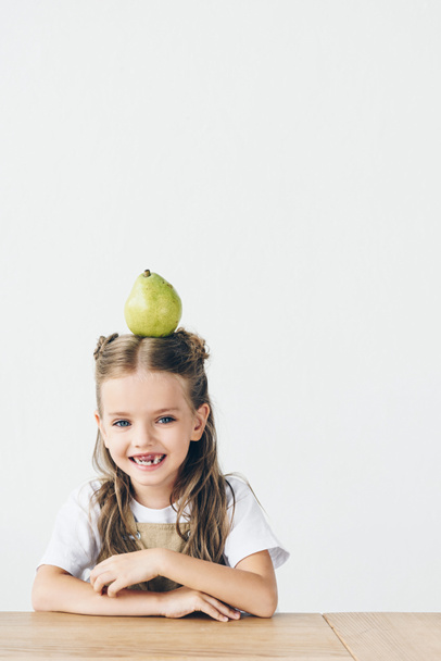 laughing little child with ripe pear on head isolated on white - Photo, Image
