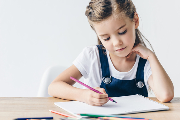 concentrated little schoolgirl drawing with color pencils isolated on white - Photo, Image