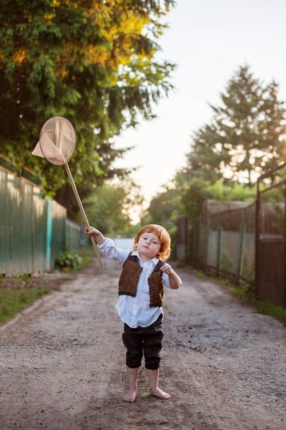 A boy with a net on a country road - Фото, изображение