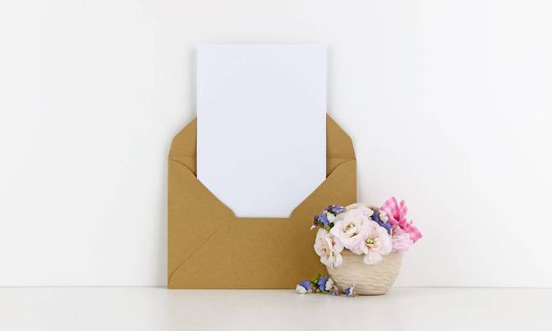 leere Postkarten-Attrappe mit Bastelpapier-Umschlag und weißen Blumen - Foto, Bild