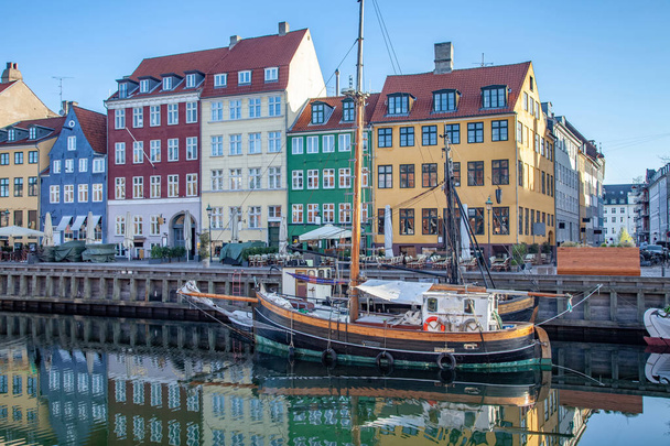 COPENHAGEN, DENMARK - MAY 6, 2018: boat and beautiful colorful buildings reflected in calm water of harbor, copenhagen, denmark - Foto, afbeelding