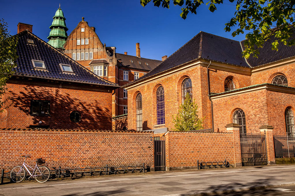красивое историческое здание с кирпичной стеной и припаркованный велосипед на уютной улице в Копенгагене, плотность
 - Фото, изображение