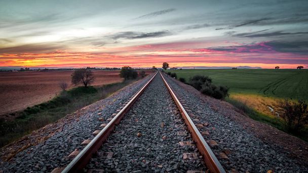 železniční tratě ve středu pole s červeným pozadím západ slunce - Fotografie, Obrázek