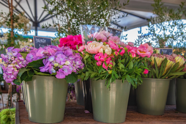 Vista de cerca de cubos con hortensia y peonías en el mercado
 - Foto, imagen