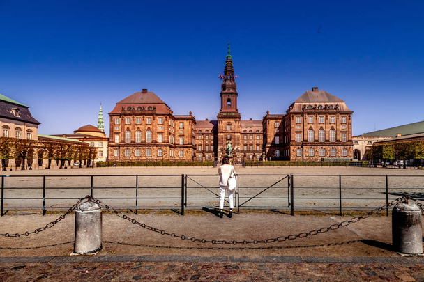 COPENHAGEN, DENMARK - MAY 6, 2018: rear view of woman taking picture of Christiansborg palace  - Photo, image
