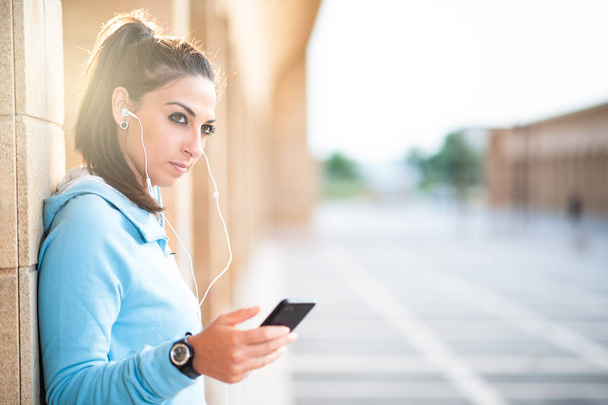 спортивная леди на открытом воздухе слушает музыку с наушниками с помощью мобильного телефона
 - Фото, изображение
