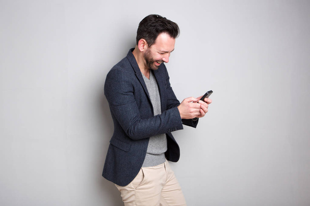 Portrait d'un homme souriant regardant un message texte sur un téléphone portable
 - Photo, image