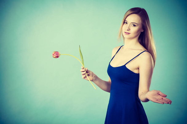 Женщина, держащая в руках романтический тюльпан. Подарок на женский день. Студия на синем фоне
. - Фото, изображение