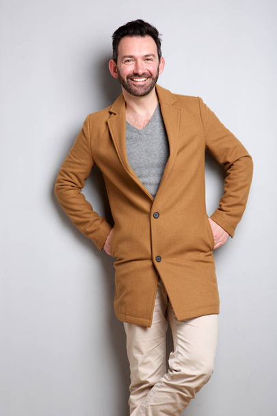 Портрет модного человека в пальто, позирующего на сером фоне
 - Фото, изображение