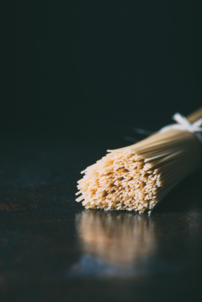 vista close-up de espaguete envolto por fita em fundo preto
  - Foto, Imagem