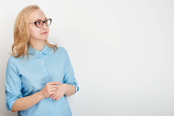 yllättynyt nainen sinisessä paidassa osoittaa sormella syrjään eristetty valkoinen studio tausta
 - Valokuva, kuva