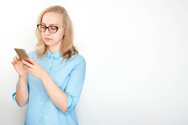 businesswoman in glasses and blue shirt texting on smartphone screen isolated on white background - Zdjęcie, obraz