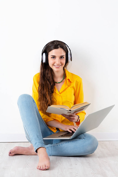Πορτρέτο του χαμογελώντας νεαρή όμορφη γυναίκα, μελετώντας και ακούγοντας τα ακουστικά - Φωτογραφία, εικόνα