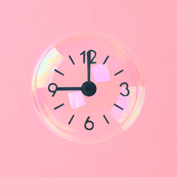 ピンクのパステル調の背景にある時計の形で矢印の付いた石鹸の泡。ミニマリズム。とらえどころのない時間の概念 - 写真・画像