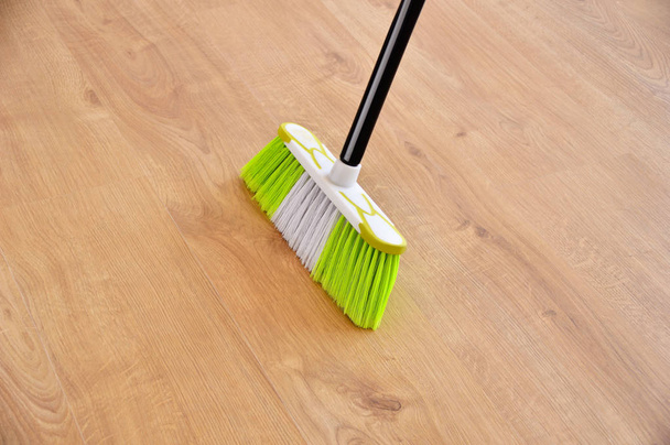 housework, cleaning and housekeeping concept - close up of  broom sweeping floor at home - Fotografie, Obrázek