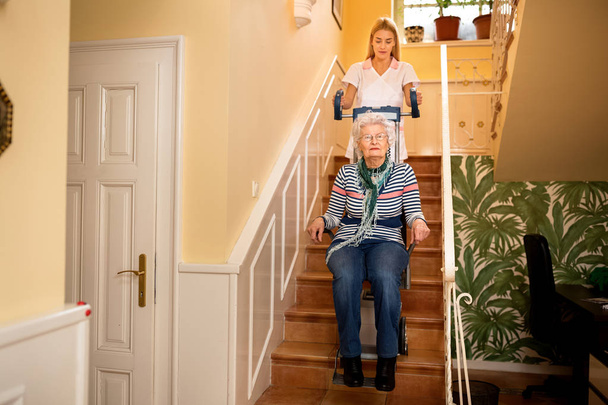Hemşire bakım evi merdiven tırmanmaya kadın kıdemli yardımcı olur. - Fotoğraf, Görsel