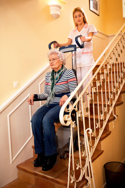 Nurse helps senior woman to climb to the stairs at nursing home - Photo, Image