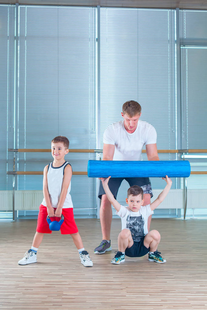 Group of children doing kids gymnastics in gym with teacher. Happy sporty children in gym. foam roller - Φωτογραφία, εικόνα