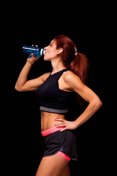 beautiful woman with bottle of water. Perfect female body isolated on black background - Photo, image