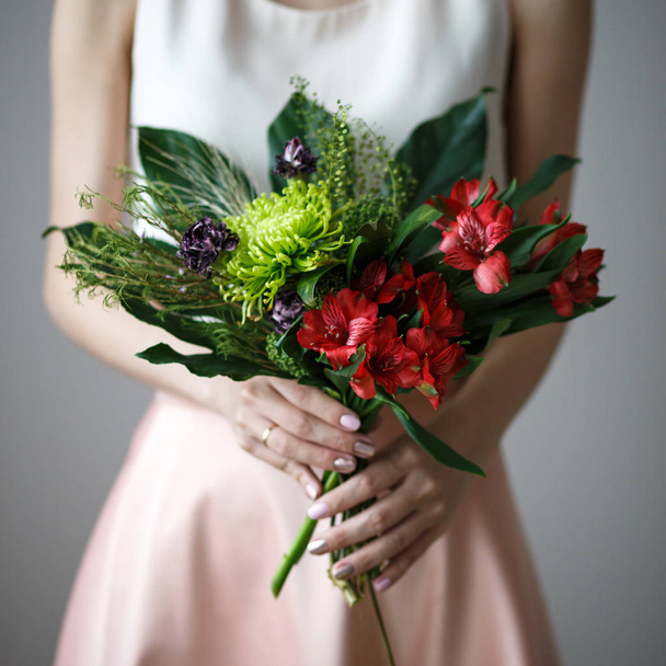 Fashion modern bouquet of different flowers in woman's hands. Romantic casual look - Foto, afbeelding