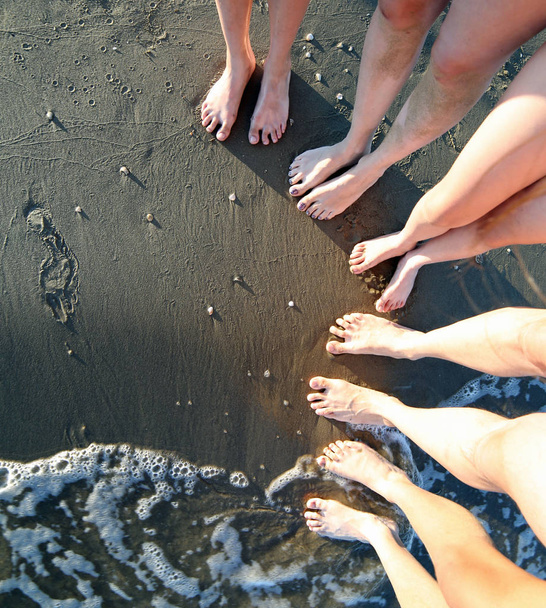 Barfuß von einer fünfköpfigen Familie mit langen Beinen am Sandstrand des Meeres im Sommer - Foto, Bild
