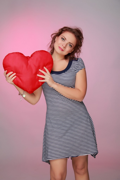Beautiful woman in a striped dress holding a big heart - Zdjęcie, obraz