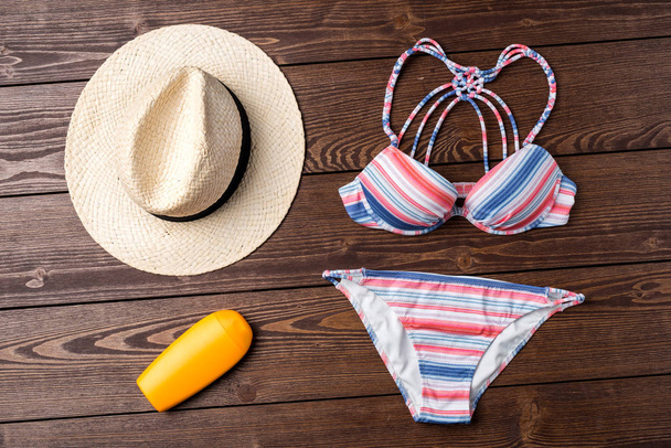 Female swimsuit with beach accessories on wooden background - 写真・画像