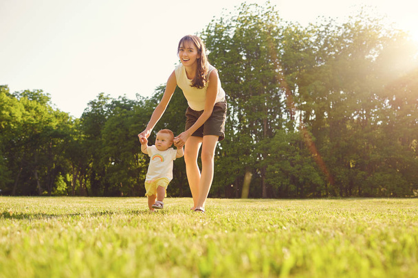 Mother and child are walking in the park at sunset . - Foto, imagen