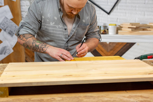 profesión, carpintería, carpintería y concepto de personas - carpintero que trabaja con tablón de madera en el taller
 - Foto, Imagen