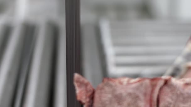 Człowiek rzeźnik cięcia surowego mięsa na Piła taśmowa w fabryce - Materiał filmowy, wideo