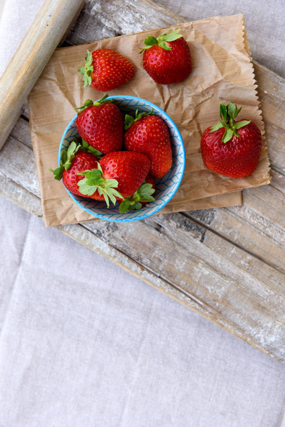 Fresh strawberries in a bowl in a wooden tray on a table. Top view. Selective focus. Copy space. - Fotó, kép
