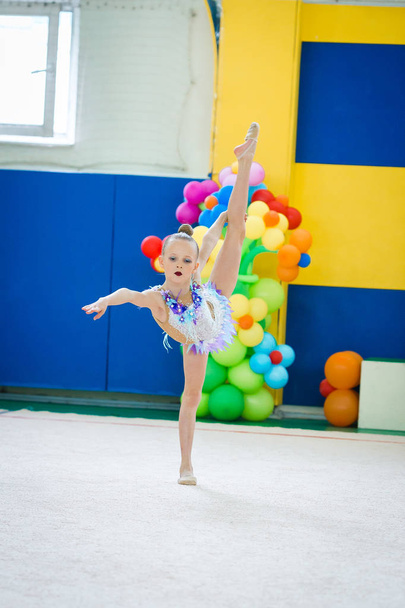 Bella piccola ginnasta attiva ragazza con le sue prestazioni sul tappeto - Foto, immagini