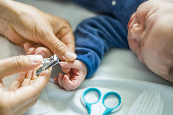 Mother cuts fingernails of her newborn baby boy in the hospital - 写真・画像