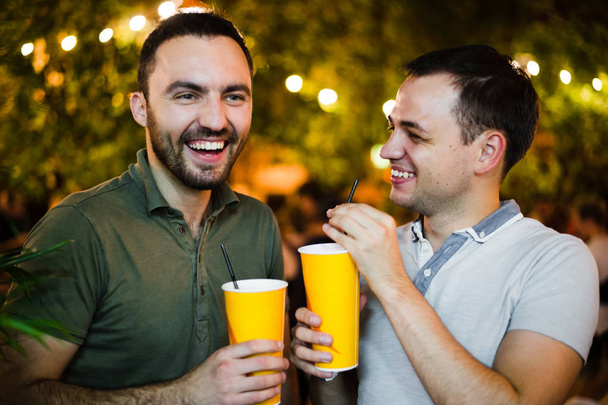 Алкоголики пьют и веселятся в открытом кафе или парке. Улыбающаяся пара алкогольная дружба
. - Фото, изображение