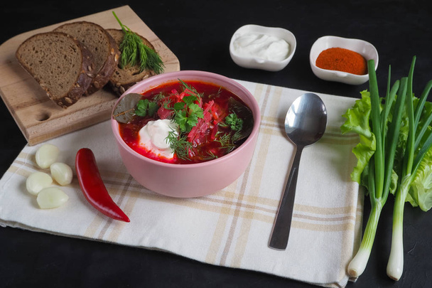 Traditionele Russische Oekraïense Borsjt met bonen op de kom. Plaat van rode biet wortel soep borsch op zwarte lijst. - Foto, afbeelding