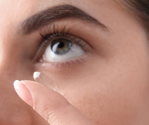 Young woman putting contact lens in her eye, closeup - Foto, imagen