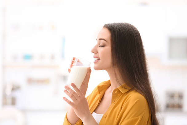 Beautiful young woman drinking milk at home - Foto, Bild