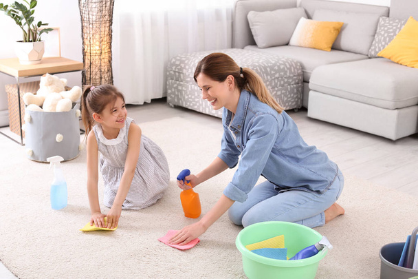 Housewife with daughter cleaning carpet in room together - Fotografie, Obrázek