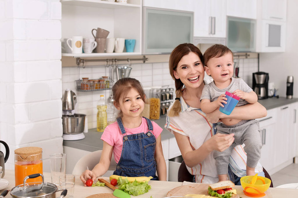 Домохозяйка готовит ужин с детьми на кухне
 - Фото, изображение