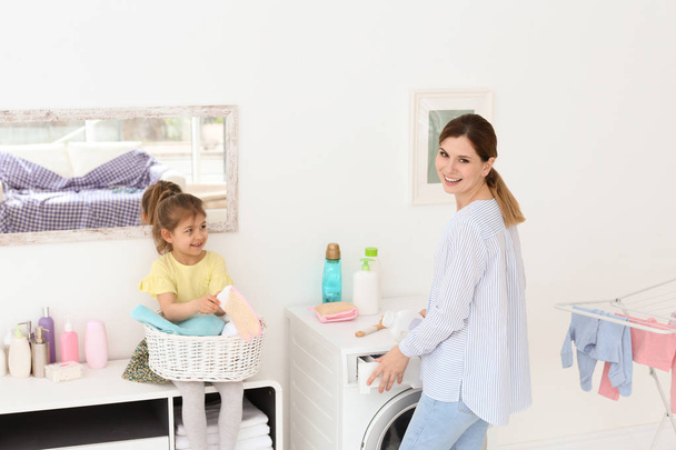 Housewife with little daughter doing laundry at home - Foto, imagen