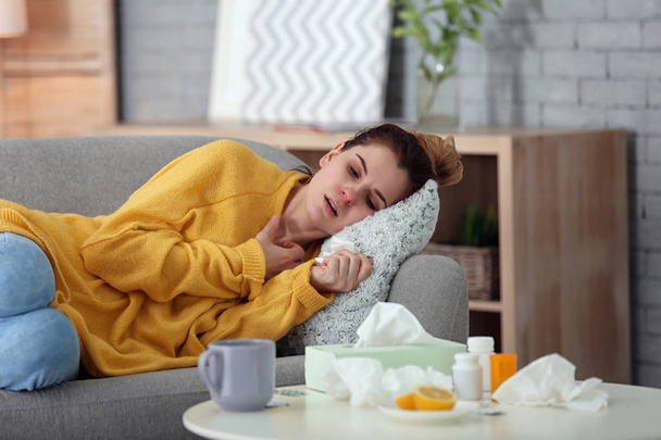 Sick woman suffering from cold on sofa at home - Foto, Imagen